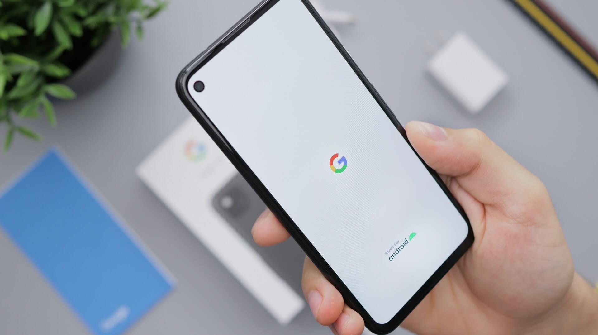 En hand som håller en mobil med Google logo på skärmen