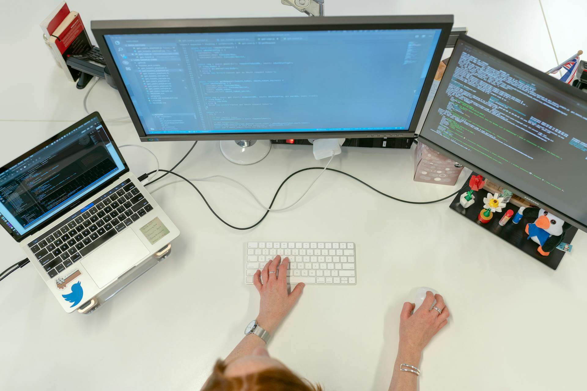 En person som utvecklar hemsida framför 2 monitorer och en laptop