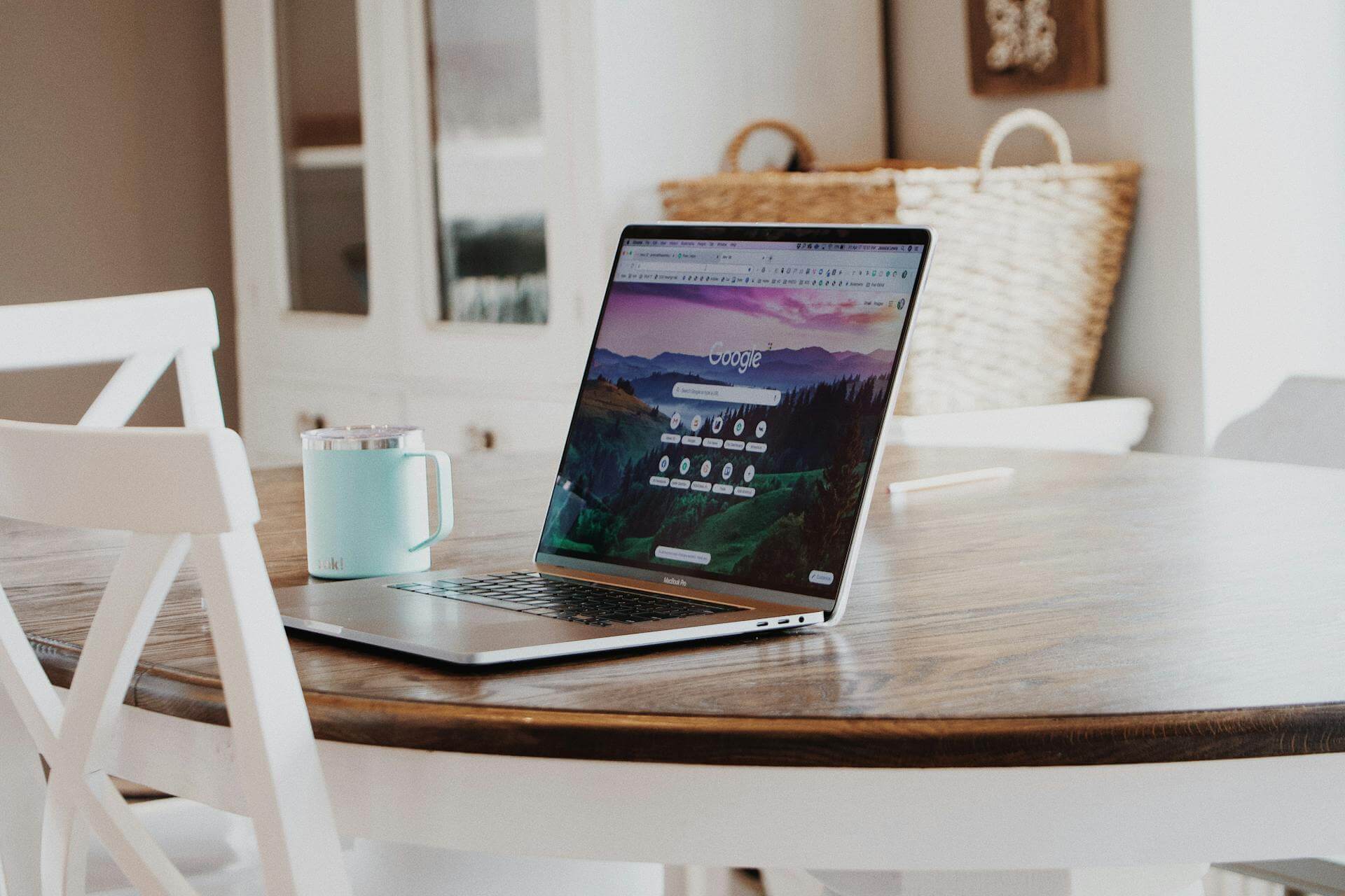 En Mac Book på ett bord med Google startsida på skärmen