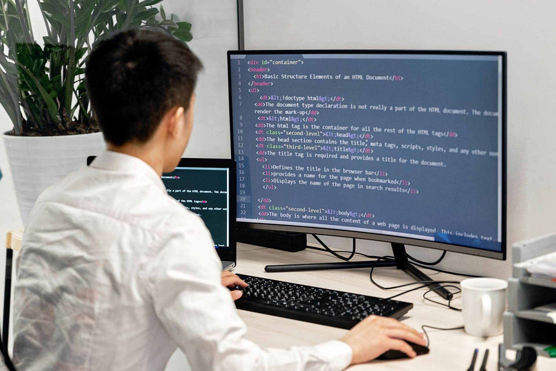 En man som sitter vid sitt skrivbord och jobbar med html