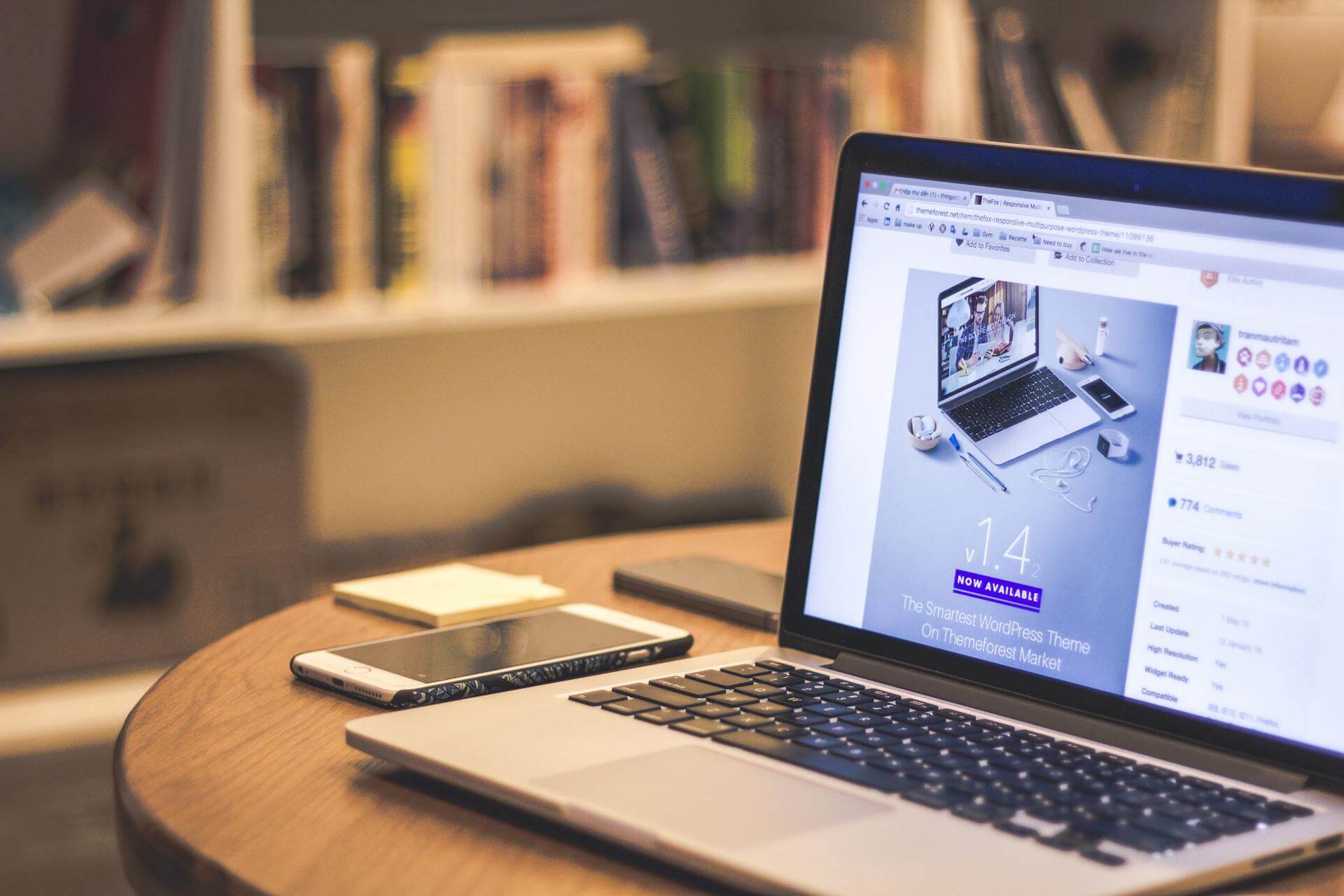 En mobil och en laptop på ett bord med WordPress premium tema på skärmen