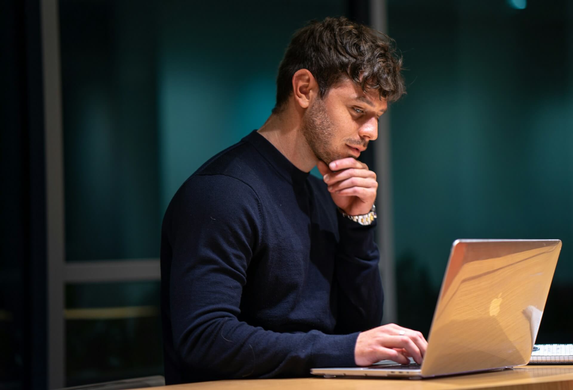 En man som tänker och funderar över sin hemsida framför sin laptop