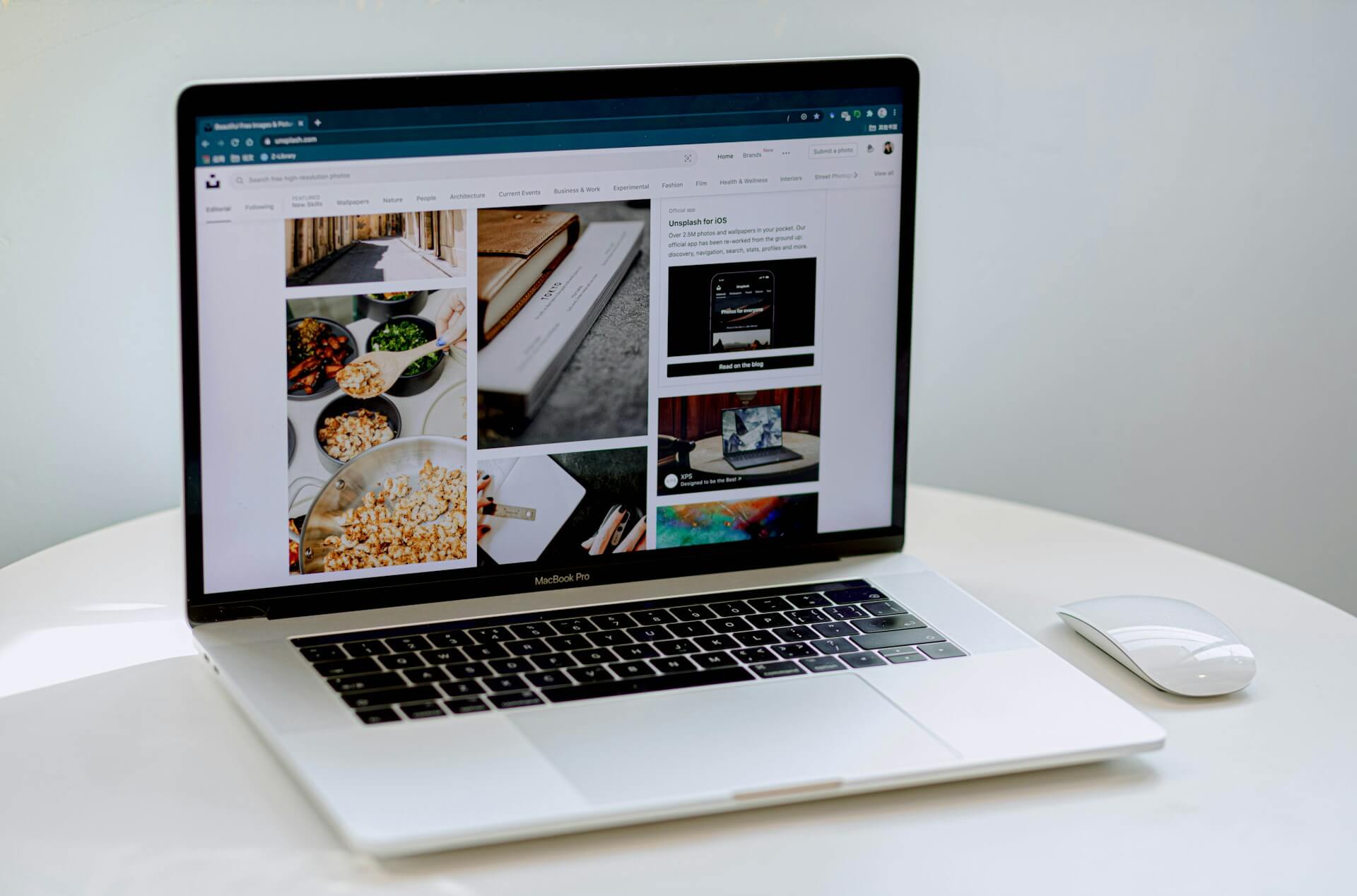 En datamus och en laptop på ett bord med hemsidan Unsplash på skärmen