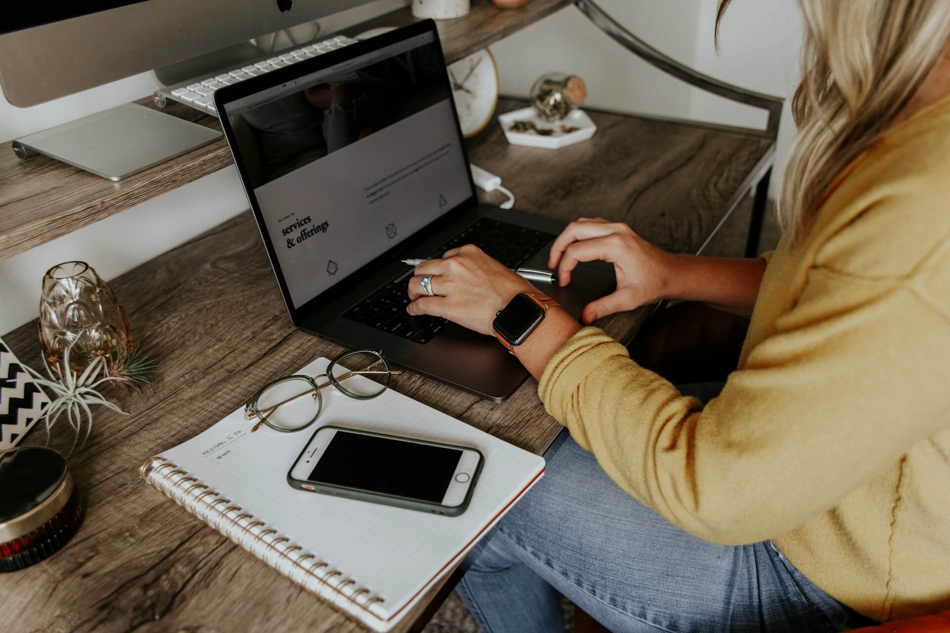 En person som sitter framför sin laptop vid sitt skrivbord och jobbar